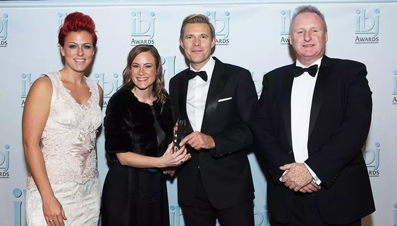 Two women and two men posing with the ibj chrystal award they just won