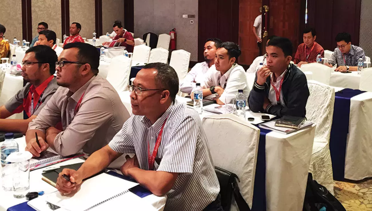 A group of people listening to a presenter in a conference room