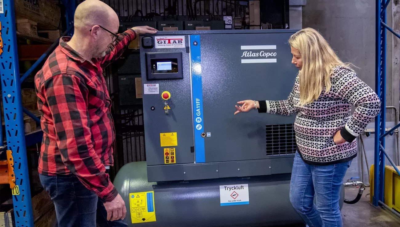 Two people standing by a compressor