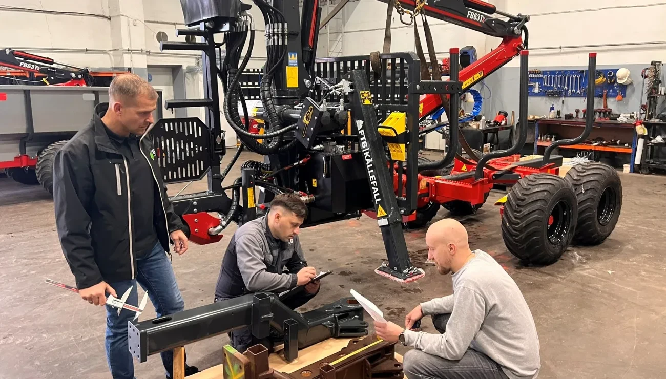 Forest crane and trailer with three men discussing spareparts
