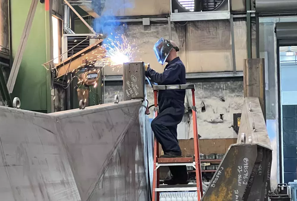 Warehouse worker welding from a ladder