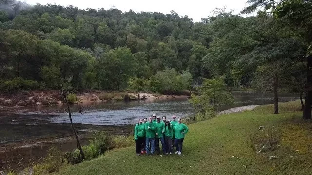 Team with green shirts by a river