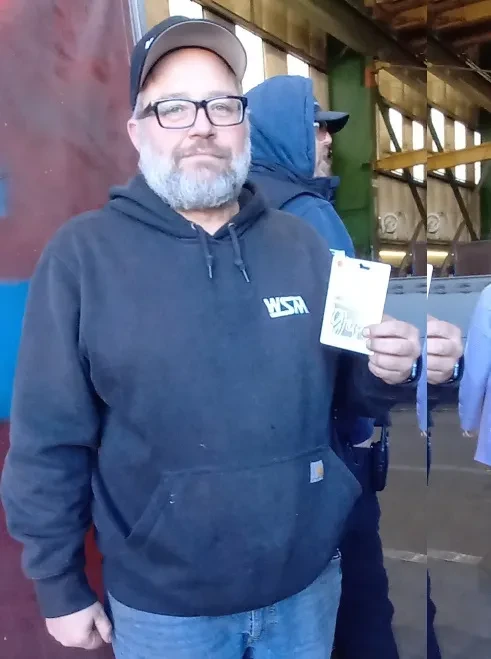 Man with hat, glasses and holding a certificate
