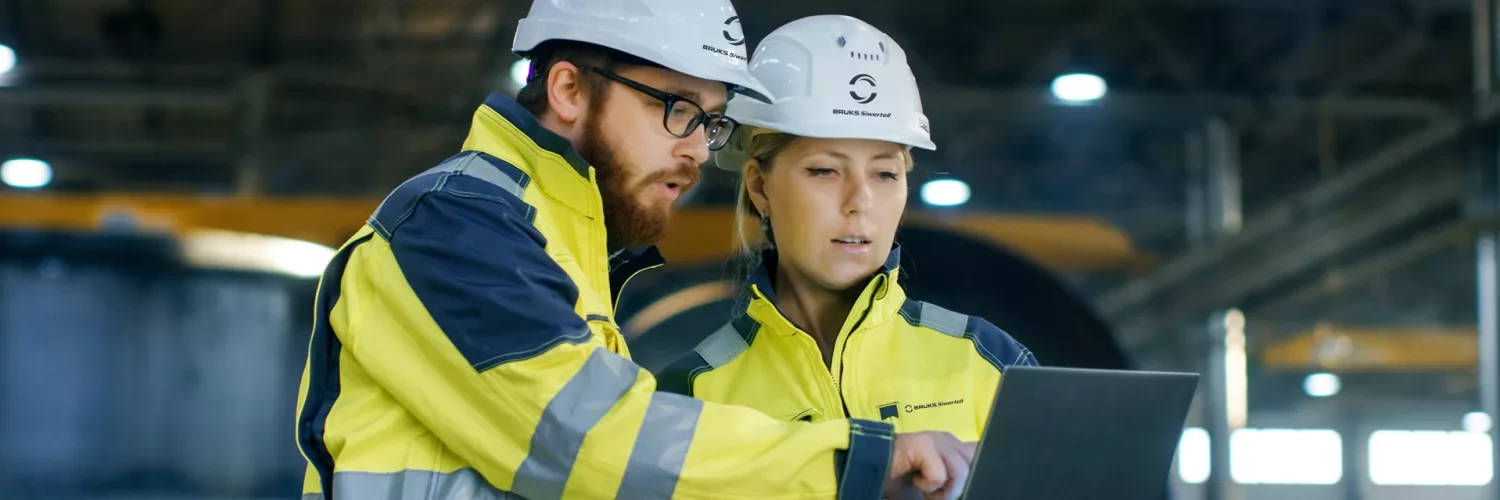Man and woman with hardhats looking at screen