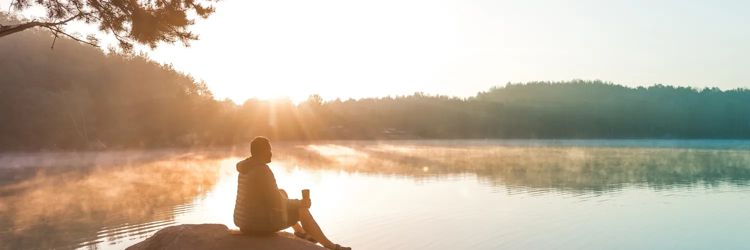 Person sitting on rock in front of water