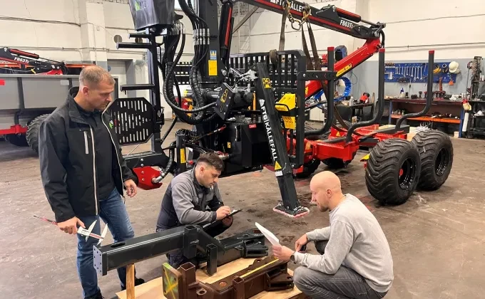 Forest crane and trailer with three men discussing spareparts